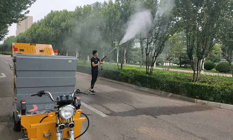 Pressure washer truck spraying pesticides on green trees