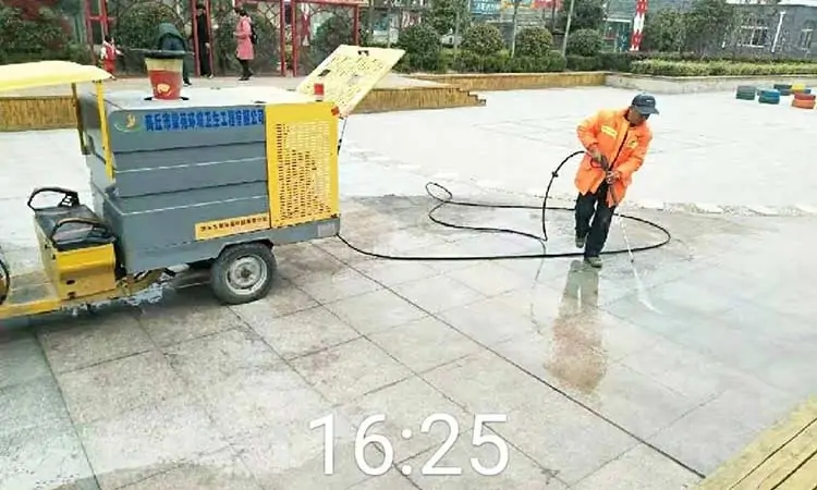 The small street washers cleans the ground of the park square