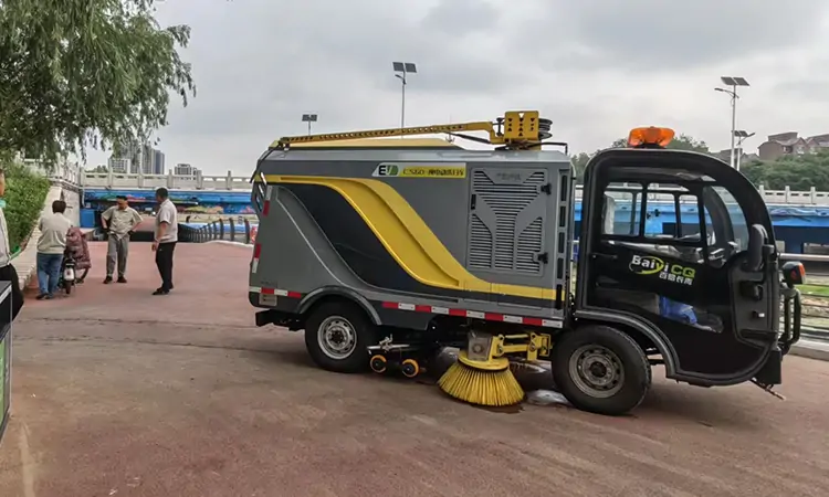 The Electric Road Sweeper Is Operating In A City Street Park